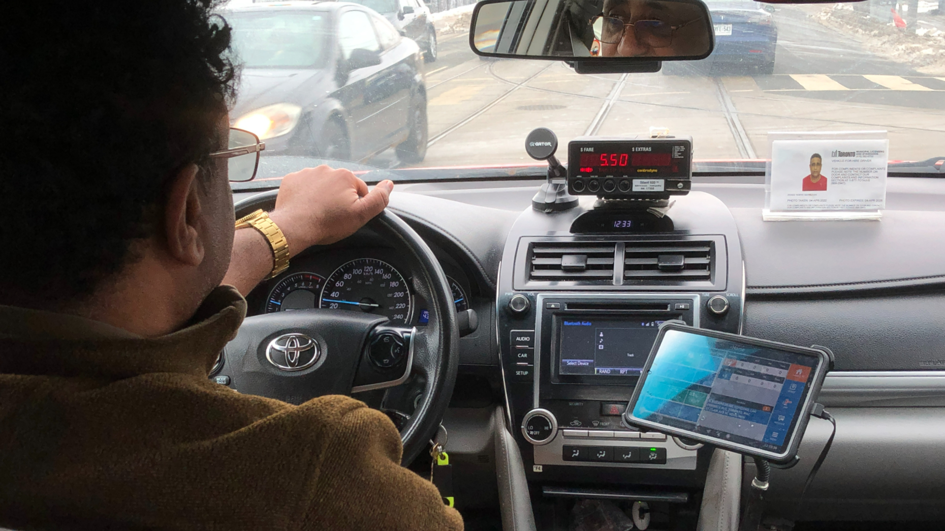 A man with one hand on a steering wheel while driving