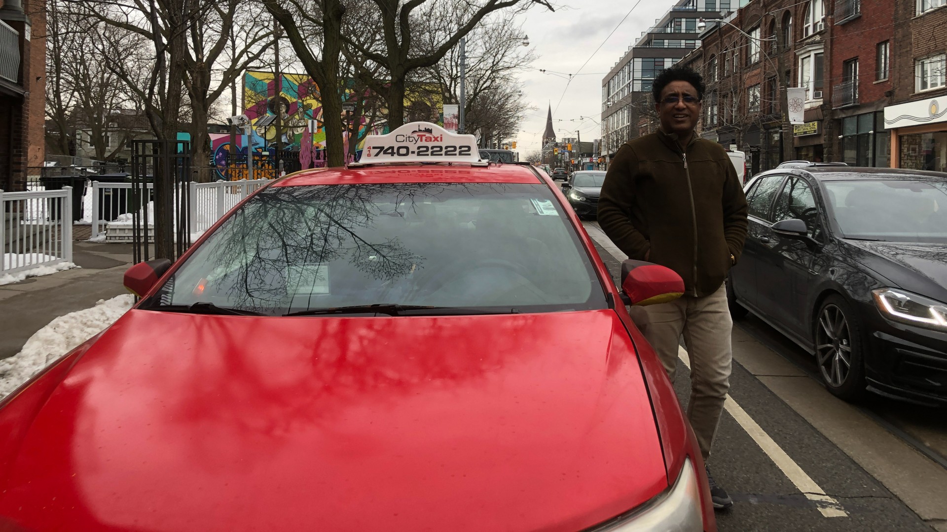 A man standing beside a red car