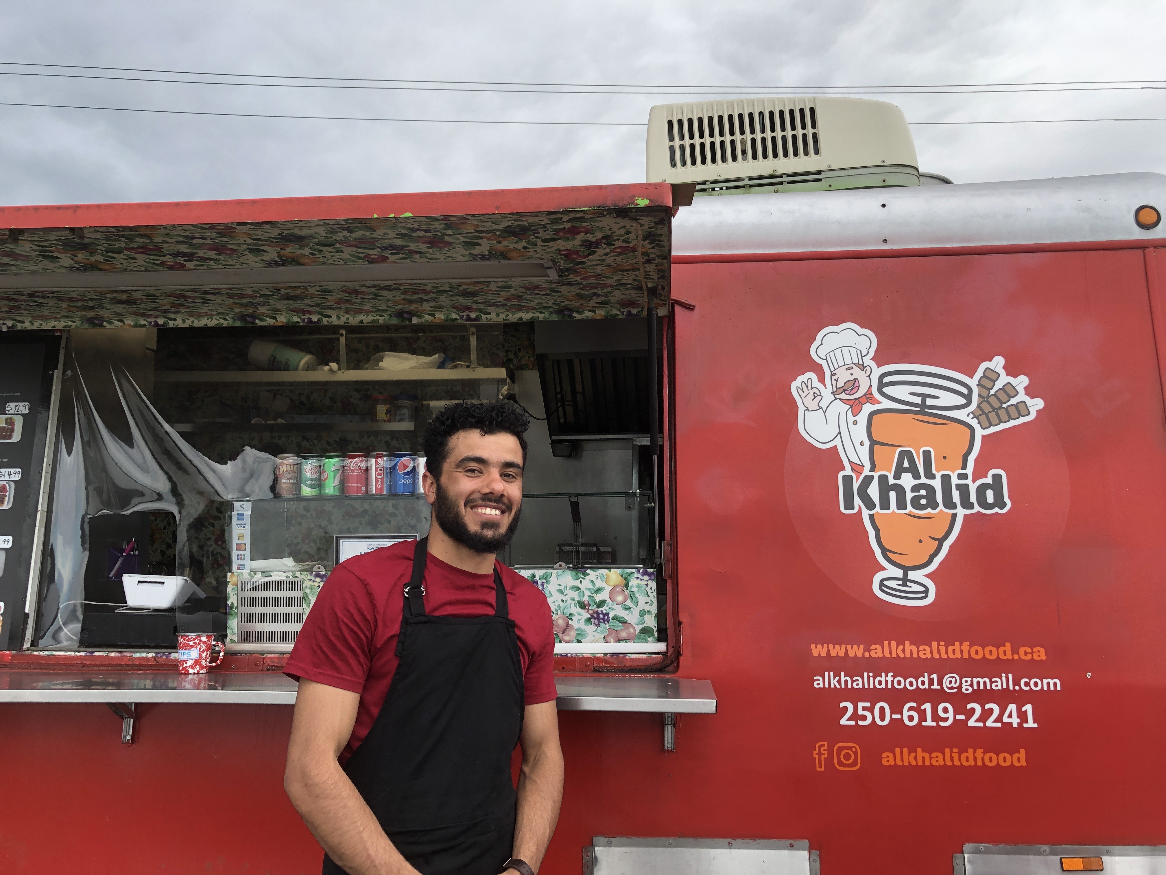 A man standing in front of the window of a red food truck