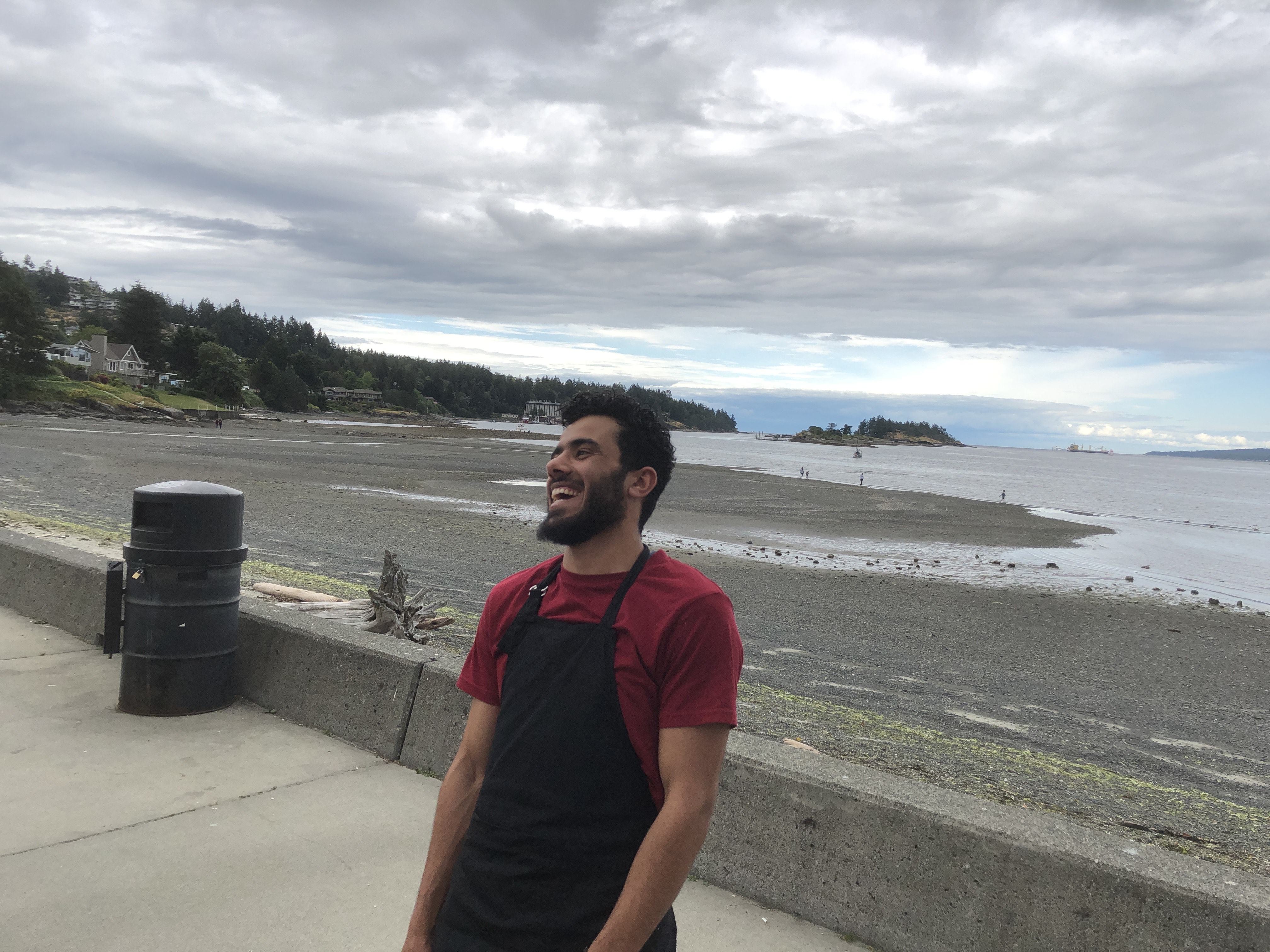 A man standing near the beach and ocean smiling